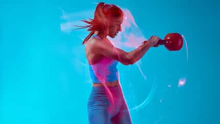 Eine weibliche Bodybuilderin, die Kettlebell im Studio hebt. 