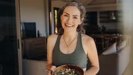 Fröhliche Frau, die einen Gemüsesalat aus einer Schüssel isst