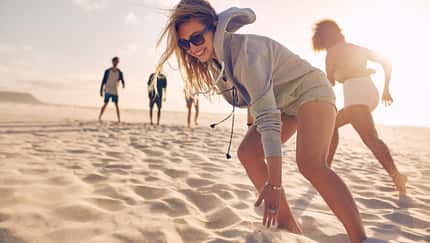 Young woman running race with friends at the beach