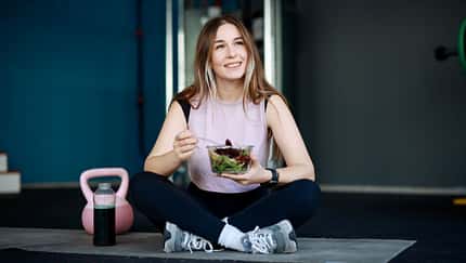 Eine junge Frau isst einen Salat