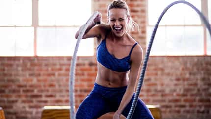 Sportliche junge Frau trainiert intensiv CrossFit mit Seil