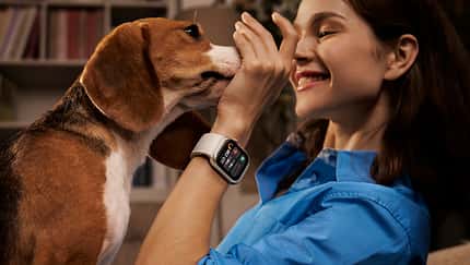 Eine Frau spielt mit ihrem Hund, sie trägt die HUAWEI WATCH D2
