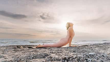 Frau macht Cobra-Position am Strand