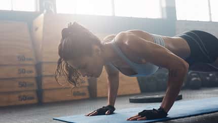Shot,Of,Young,Woman,Doing,Push-ups,At,The,Gym.,Muscular