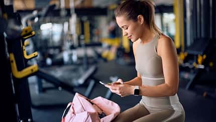 Frau in Sportkleidung schaut auf ihr Handy