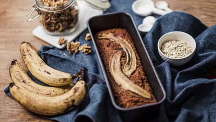 Bananenbrot mit Bananen an der Seite auf einem blauen Tuch