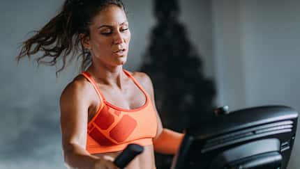 Frau im Sport-Bh am Crosstrainer