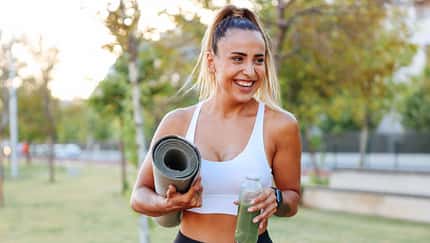 Eine Frau trinkt einen Green Smoothie nach dem Training