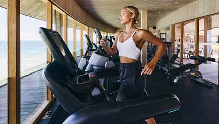 Frau trainiert mit Meerblick auf einem Crosstrainer