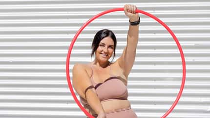 Eine kurvige Frau in Sportkleidung mit einem Hula-Hoop-Reifen