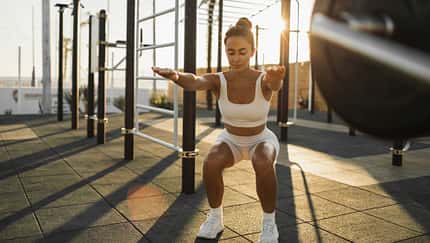 Eine Frau macht draußen Squats in der Sonne