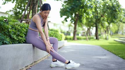 Woman Massaging Sore Leg After Exercise