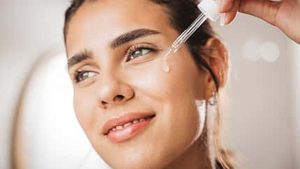 Young woman applying serum on face Young woman applying serum on face