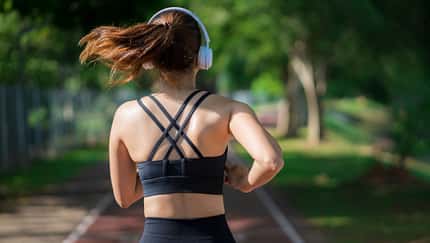 Eine Frau von hinten, wie sie durch die Natur joggt Eine Frau von hinten, wie sie durch die Natur joggt