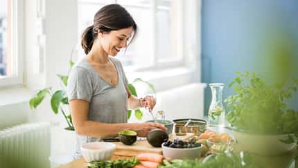 Eine Frau bereitet gesundes Essen in der Küche zu Eine Frau bereitet gesundes Essen in der Küche zu