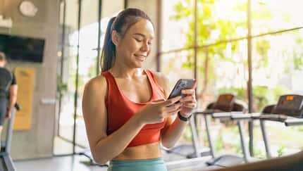 Eine Frau in Sportkleidung schaut auf ihr Handy Eine Frau in Sportkleidung schaut auf ihr Handy