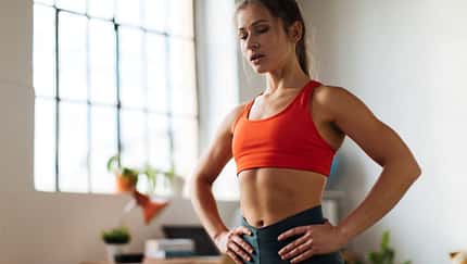 Eine trainierte Frau macht Bauchübungen im Stehen Eine trainierte Frau macht Bauchübungen im Stehen