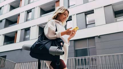 Happy Sporty Woman in a White Sweatshirt Using a Mobile Phone Outdoors