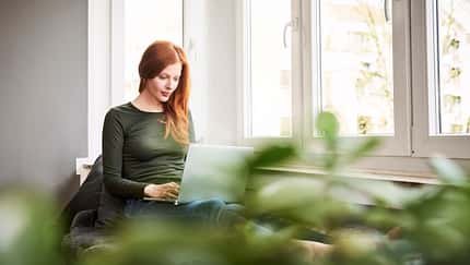 Eine rothaarige Frau arbeitet am Laptop