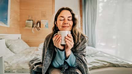 Serene woman savoring the aroma of coffee in her cozy bedroom Serene woman savoring the aroma of coffee in her cozy bedroom