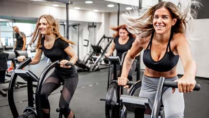 Smiling Young Women Using Exercise Bike
