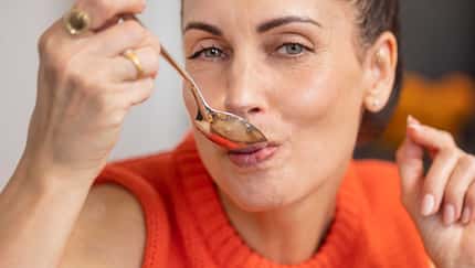 Nahaufnahme einer Frau in rotem Pollunder mit Löffel im Mund