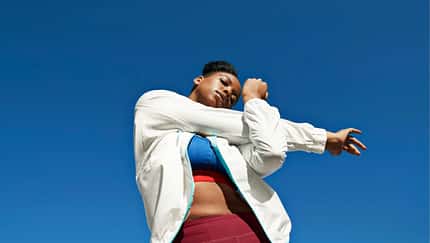 Froschperspektive einer Frau, die ihre Schulter dehnt. Hintergrund nur blauer Himmel Froschperspektive einer Frau, die ihre Schulter dehnt. Hintergrund nur blauer Himmel