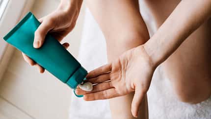 Hände, die Creme aus einer grünen Tube auftragen Hände, die Creme aus einer grünen Tube auftragen