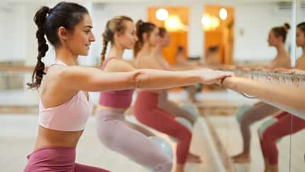 Barre fit exercise class. Group of people in a row at a barre workout class