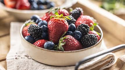 Ripe sweet different berries in a bowl on kitchen table.