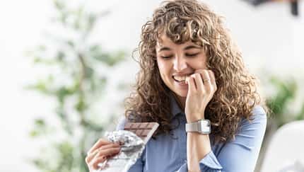 Frau hält eine Tafel Schokolade in der Hand und lächelt diese an Frau hält eine Tafel Schokolade in der Hand und lächelt diese an