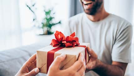 Cheerful young man receiving a gift from his girlfriend.