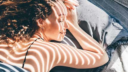 Frau liegt im Halbschatten in der Sonne