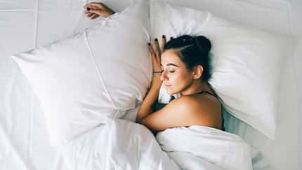 Frau schläft in einem Hotelbett mit frischer weißer Bettwäsche Frau schläft in einem Hotelbett mit frischer weißer Bettwäsche