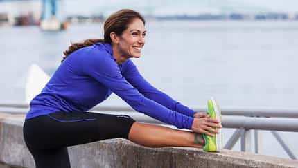 Eine Frau in Sportkleidung stretcht ihre Beine 