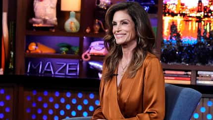 Cindy Crawford sitzt lächelnd auf einem Sessel