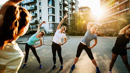 Eine Sportgruppe von Frauen wärmt sich im der Stadt vor dem Laufen gehen auf