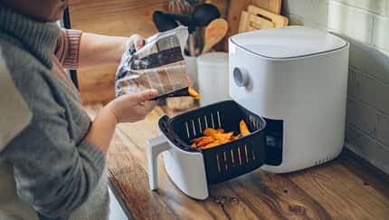 Eine Frau bereitet Kartoffeln im Airfryer zu Eine Frau bereitet Kartoffeln im Airfryer zu
