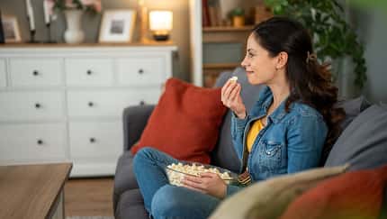 Eine Frau sitzt auf dem Sofa und isst Popcorn Eine Frau sitzt auf dem Sofa und isst Popcorn