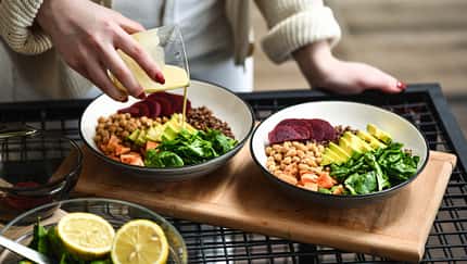 Frau bereitet einen leckeren Salat mit Kichererbsen zu und Dressing hinzu