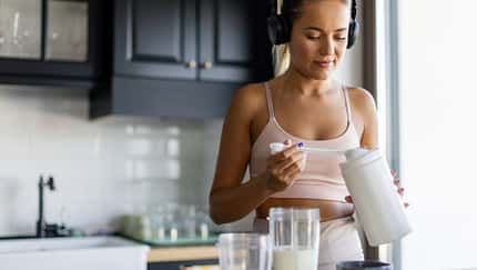 Eine Frau bereitet mit einem Supplement einen Smoothie zu Eine Frau bereitet mit einem Supplement einen Smoothie zu