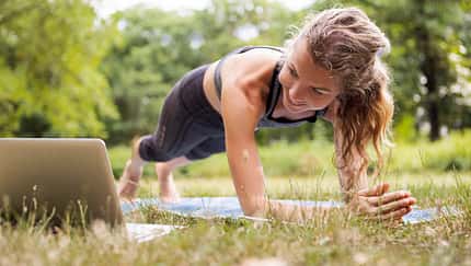 Frau macht im Park ein Workout mit einem Youtube-Video über ihren Laptop Frau macht im Park ein Workout mit einem Youtube-Video über ihren Laptop