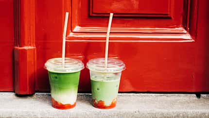 Zwei Iced Strawberry Matcha Lattes vor einer roten Haustür Zwei Iced Strawberry Matcha Lattes vor einer roten Haustür