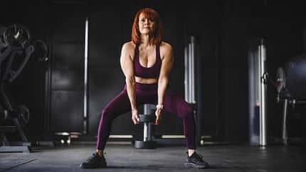 Eine trainierte Frau macht Kniebeugen mit einer Kettlebell