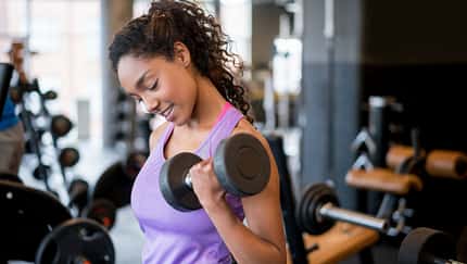 Eine junge Frau trainiert im Fitnessstudio mit Kurzhanteln