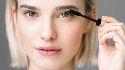 Frau schminkt sich und trägt Mascara auf