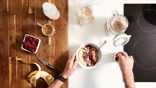 Sicht von oben auf einen Tisch: Mann bereitet Porridge zu