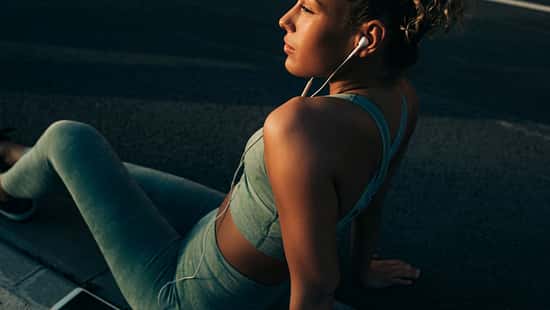 Junge Frau, die während des Trainings Musik über ihre Kopfhörer hört