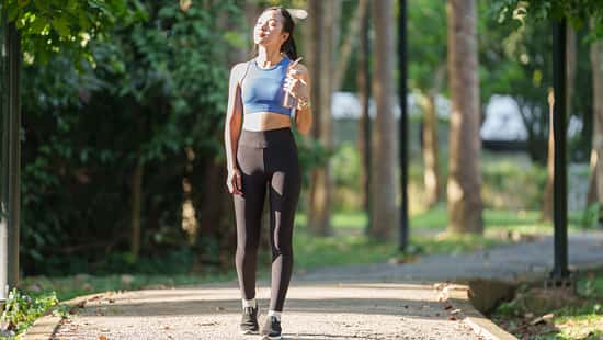 Young,Asian,Woman,,Dressed,In,Sportswear,,Walks,Along,A,Park