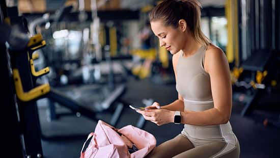 Frau in Sportkleidung schaut auf ihr Handy